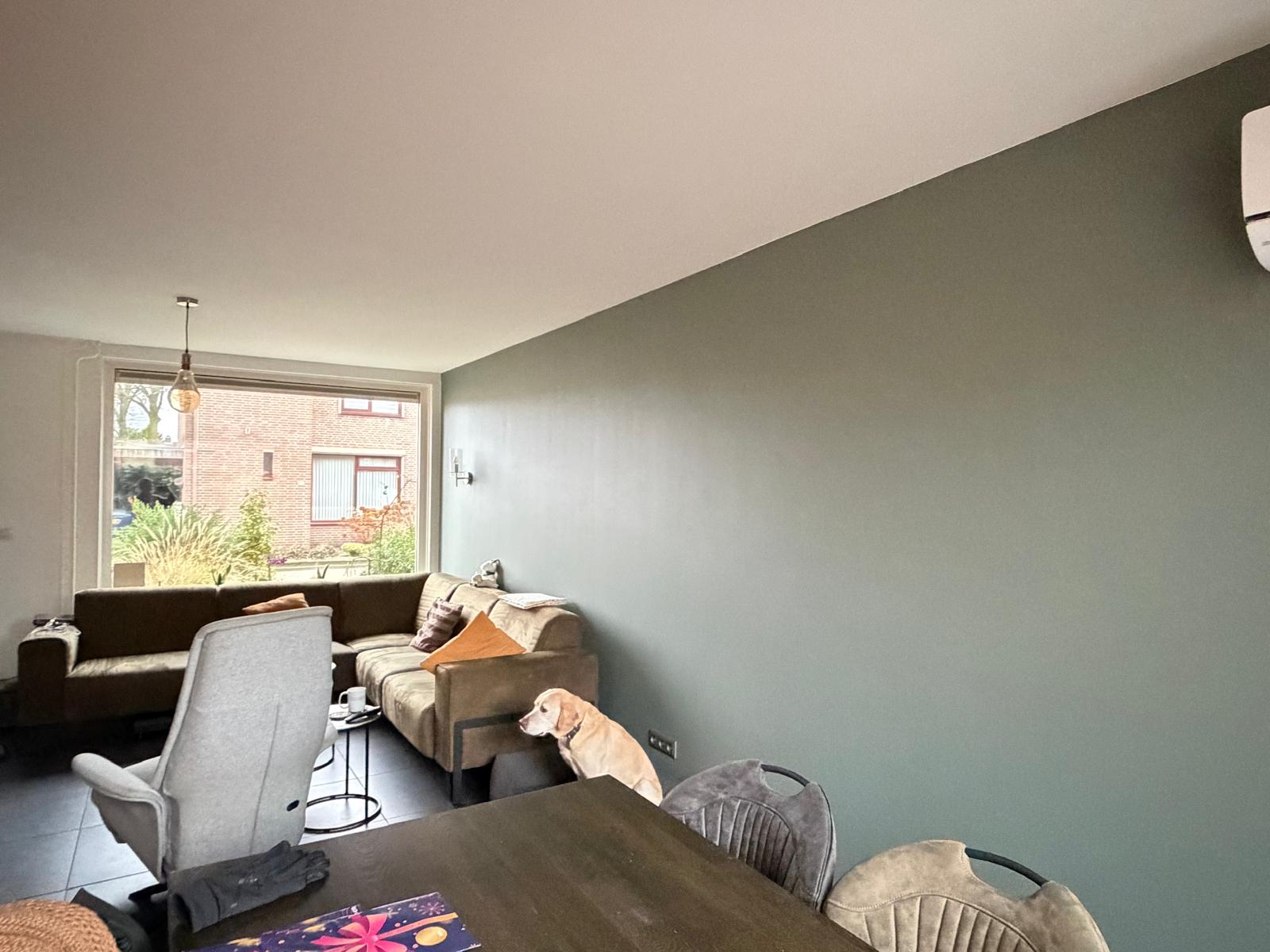 Afgewerkte woonkamer met gladde wanden en een groene accentmuur