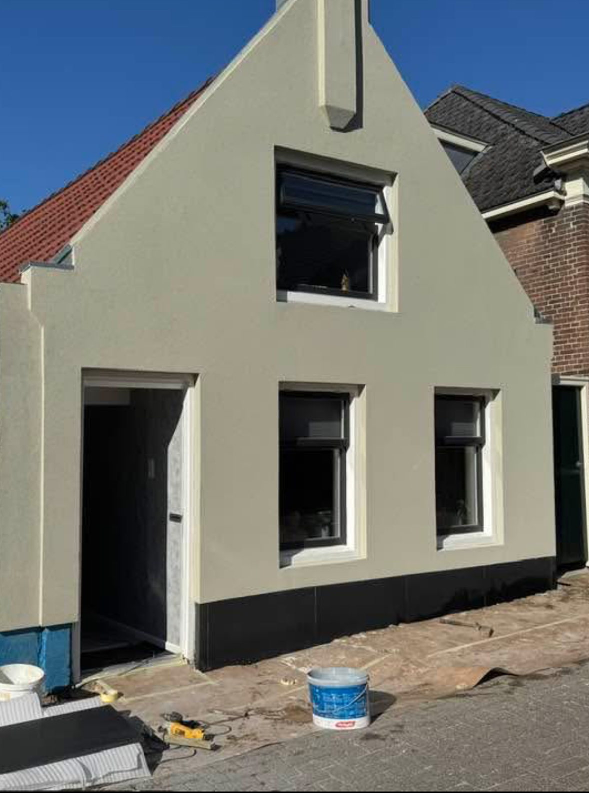 Puntgevel in zachtgroen stucwerk met witte kozijnranden en donkere plint