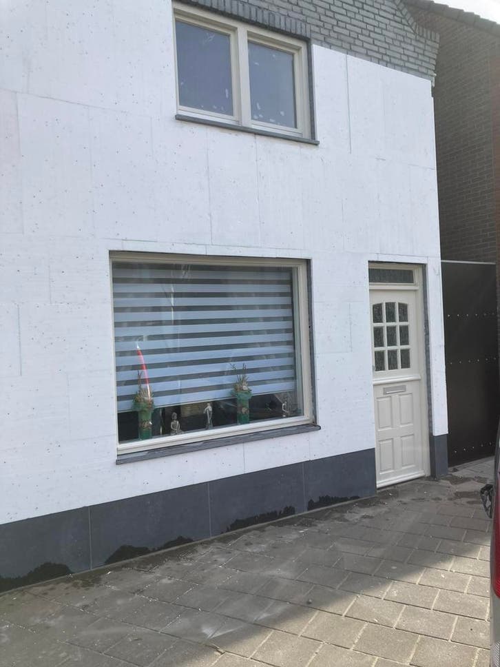 Smalle voorgevel wit gestuct, met donkere plint