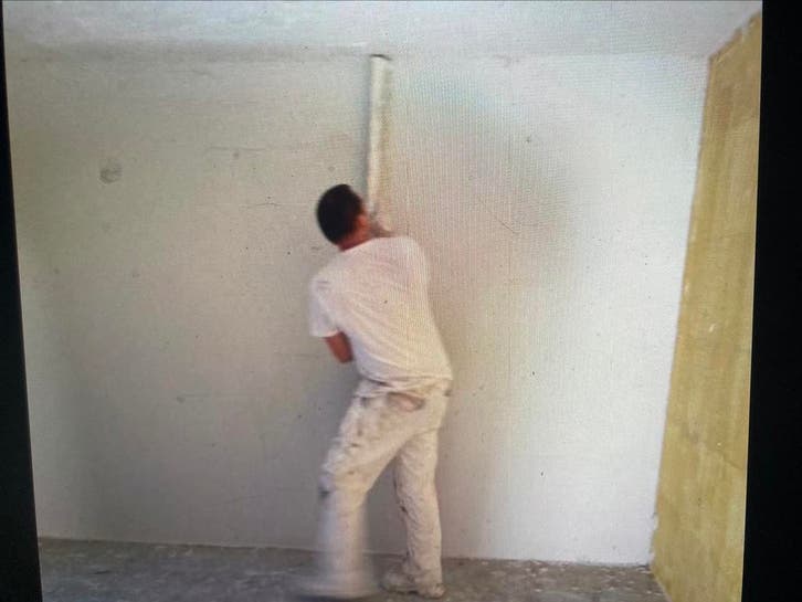 Stucadoor in witte werkkleding zet een wand op