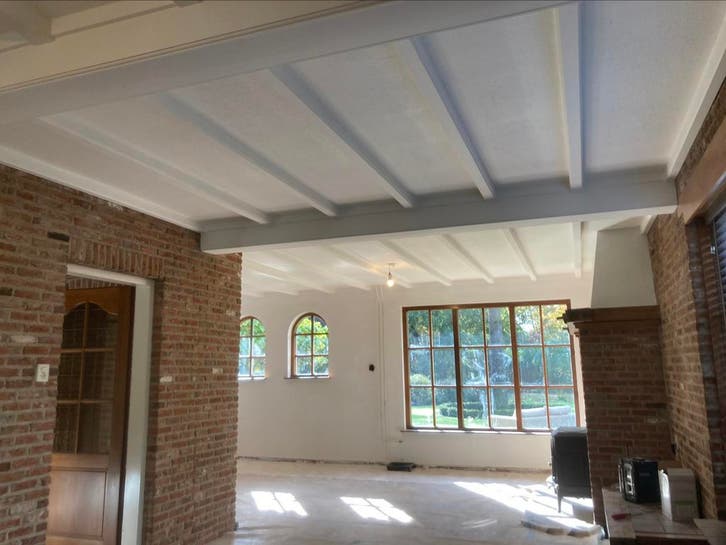 Gerenoveerde kamer met witte balkenplafond en gestucte wanden
